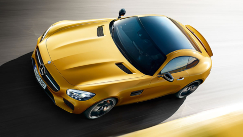 An orange AMG GTS, vibrant and dynamic, cuts through the air, embodying the thrill of speed and the epitome of engineering elegance in Saint-Tropez